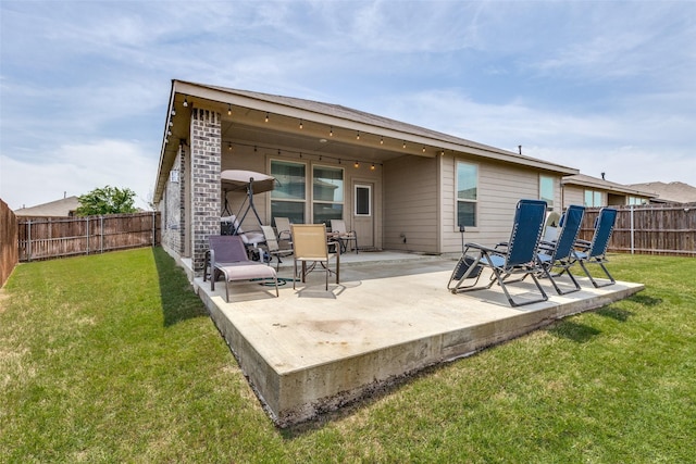 rear view of property featuring a lawn, a fenced backyard, and a patio