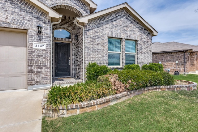 view of exterior entry featuring a yard and stone siding