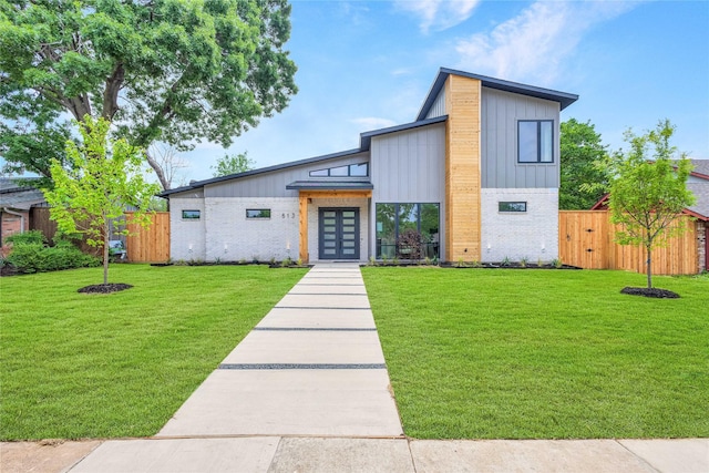 modern home featuring a front lawn, board and batten siding, brick siding, french doors, and fence