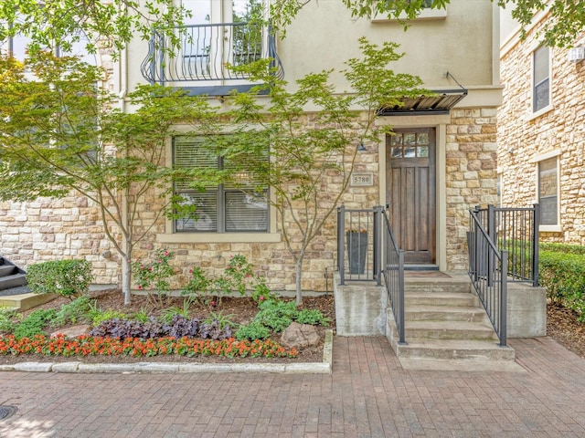 view of exterior entry with stucco siding and stone siding
