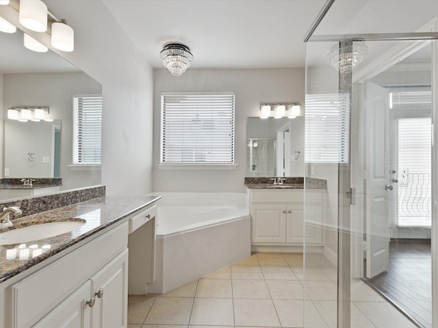 bathroom featuring a garden tub, two vanities, tile patterned floors, a shower stall, and a sink