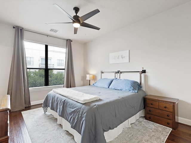 bedroom featuring visible vents, a ceiling fan, baseboards, and wood finished floors