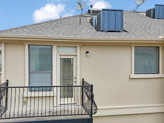 property entrance featuring a shingled roof and stucco siding