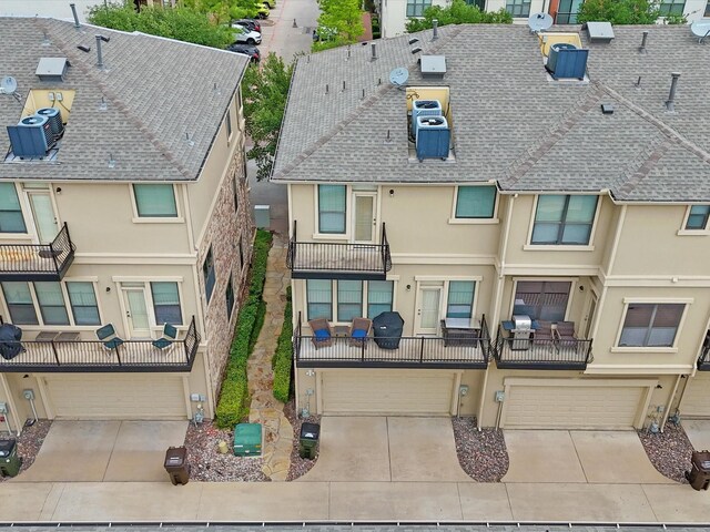 view of front of house with concrete driveway, an attached garage, a shingled roof, and stucco siding