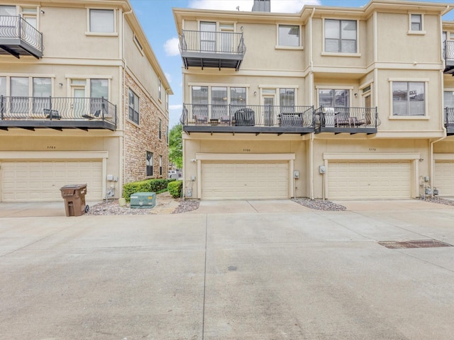 view of front facade featuring concrete driveway, an attached garage, a balcony, and stucco siding