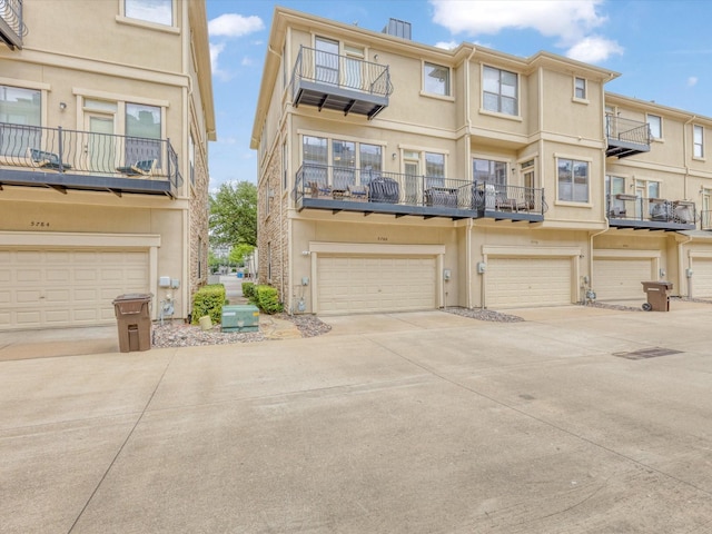 view of front of property featuring stucco siding, an attached garage, driveway, and a balcony