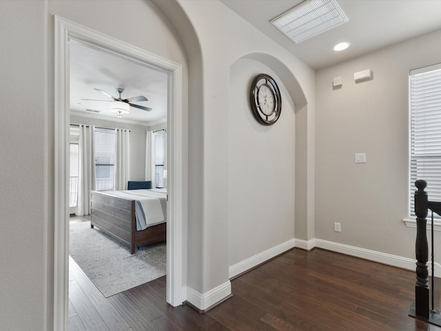corridor with visible vents, dark wood-style flooring, crown molding, and baseboards