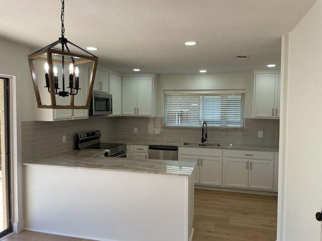 kitchen featuring light countertops, light wood-type flooring, a sink, and appliances with stainless steel finishes