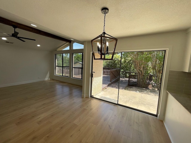 unfurnished dining area with a textured ceiling, visible vents, wood finished floors, vaulted ceiling with beams, and a notable chandelier