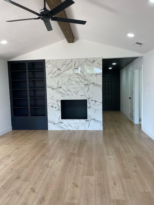 unfurnished living room featuring visible vents, lofted ceiling with beams, ceiling fan, a fireplace, and wood finished floors