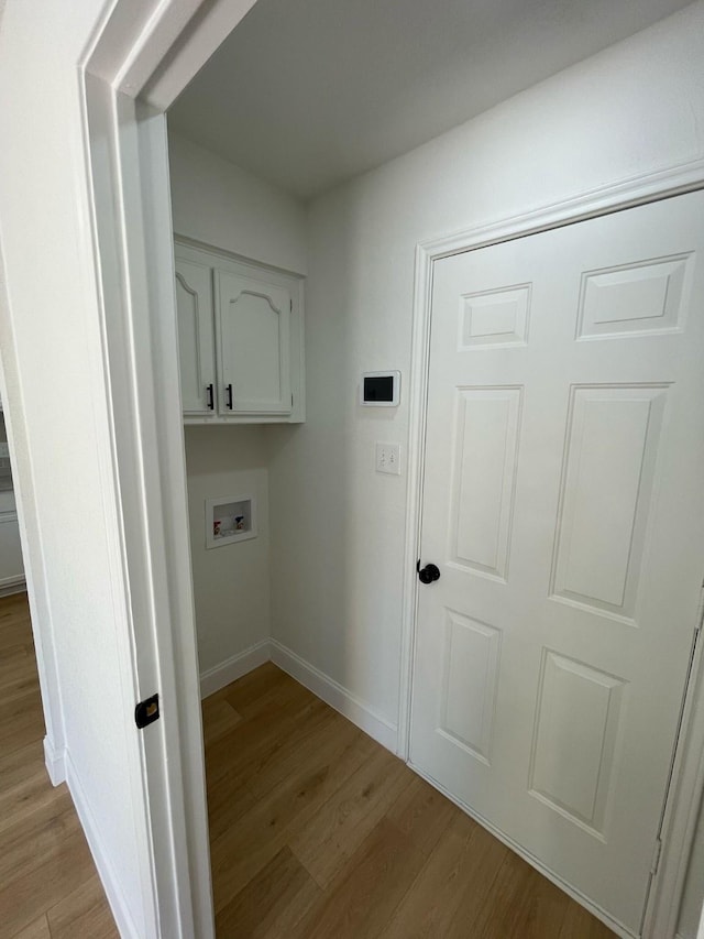laundry room with cabinet space, baseboards, light wood-style floors, and washer hookup