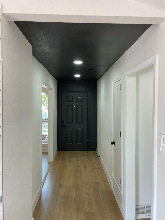 hallway featuring light wood finished floors and baseboards