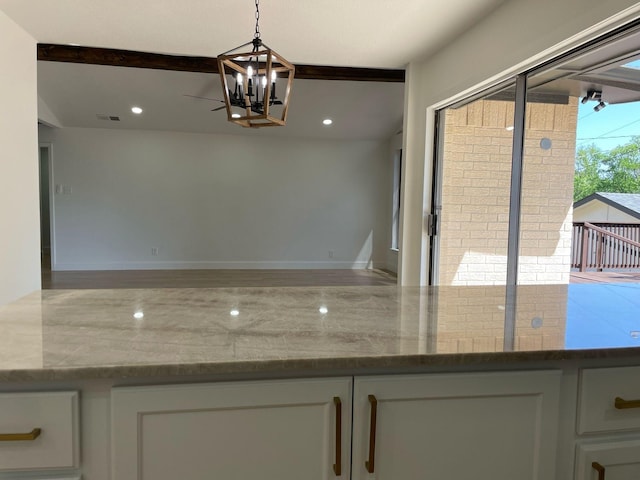 kitchen featuring dark stone countertops, visible vents, an inviting chandelier, white cabinetry, and pendant lighting