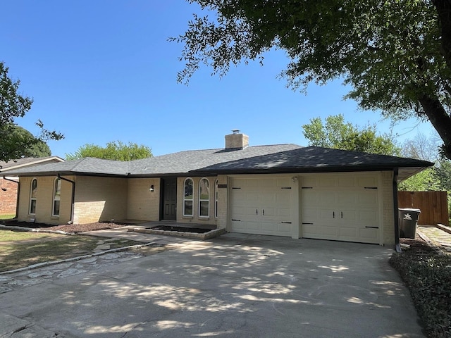 single story home featuring fence, brick siding, an attached garage, a chimney, and concrete driveway