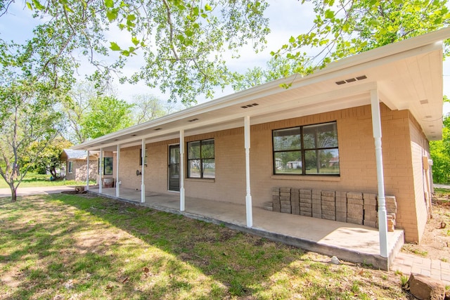 503 W College St, Rising Star, TX 76471 - rear view of property featuring brick siding, a yard, and a patio