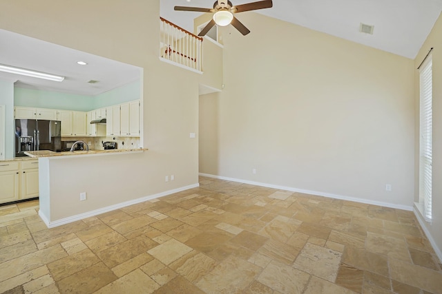 2313 Suntree, Flower Mound, TX 75022 - unfurnished living room featuring stone tile flooring, a high ceiling, ceiling fan, and baseboards