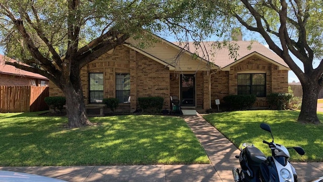ranch-style home featuring brick siding, a front lawn, and fence