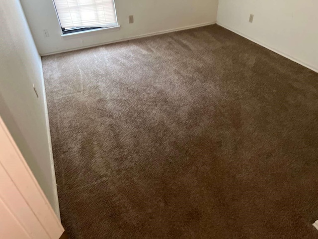 interior space with dark carpet and baseboards