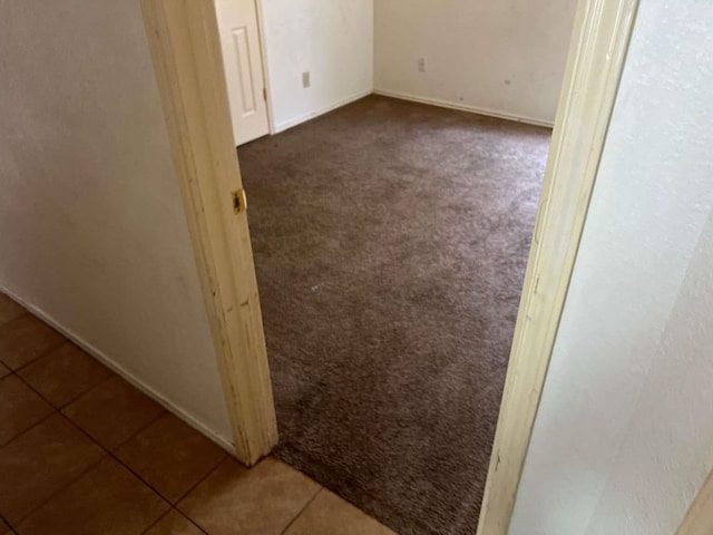unfurnished room featuring tile patterned floors, baseboards, and carpet floors