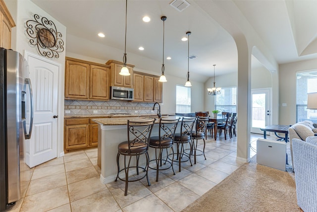 109 Thoroughbred St, Waxahachie, TX 75165 - kitchen featuring visible vents, appliances with stainless steel finishes, a kitchen island with sink, a kitchen bar, and decorative backsplash