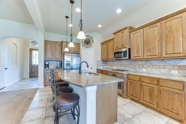 109 Thoroughbred St, Waxahachie, TX 75165 - kitchen featuring arched walkways, a breakfast bar, light stone counters, a sink, and stainless steel appliances
