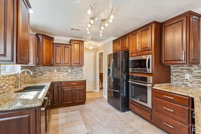 kitchen featuring visible vents, a sink, appliances with stainless steel finishes, decorative backsplash, and light stone counters