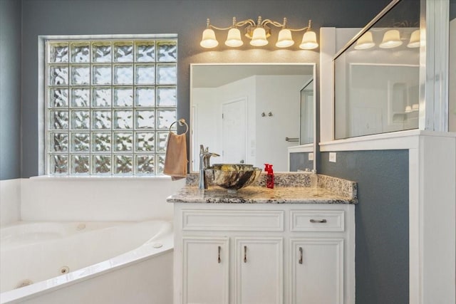 full bath with vanity and a tub with jets