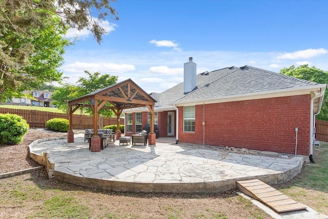 rear view of property featuring a patio, a gazebo, fence, and brick siding