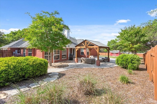 rear view of house featuring outdoor lounge area, a fenced backyard, a patio, brick siding, and a chimney
