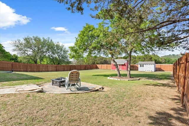 view of yard featuring a patio area, a fenced backyard, a shed, and an outbuilding