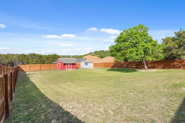 view of yard with a storage shed, a fenced backyard, and an outdoor structure