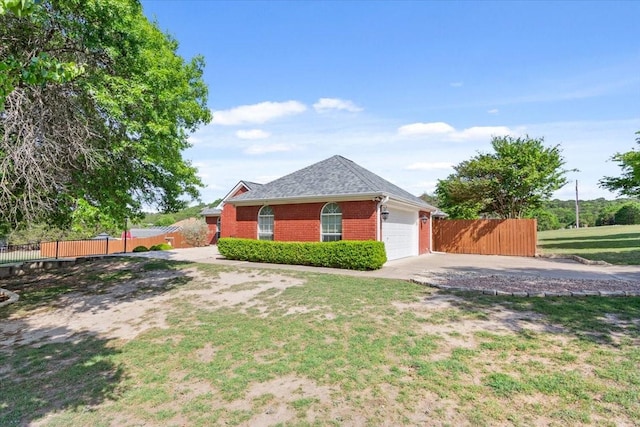 view of side of property featuring concrete driveway, brick siding, a garage, a yard, and fence