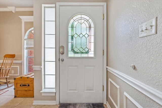 tiled foyer entrance featuring crown molding and a textured wall
