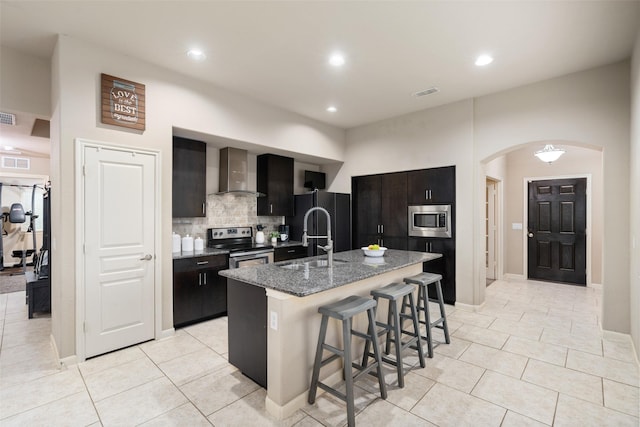 500 Harding Ln, Lavon, TX 75166 - kitchen featuring appliances with stainless steel finishes, a sink, wall chimney exhaust hood, a breakfast bar, and arched walkways