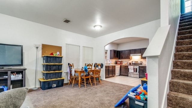 game room with arched walkways, light colored carpet, a sink, and visible vents