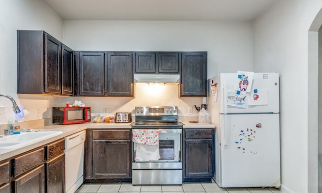 kitchen featuring white appliances, light countertops, under cabinet range hood, arched walkways, and a sink