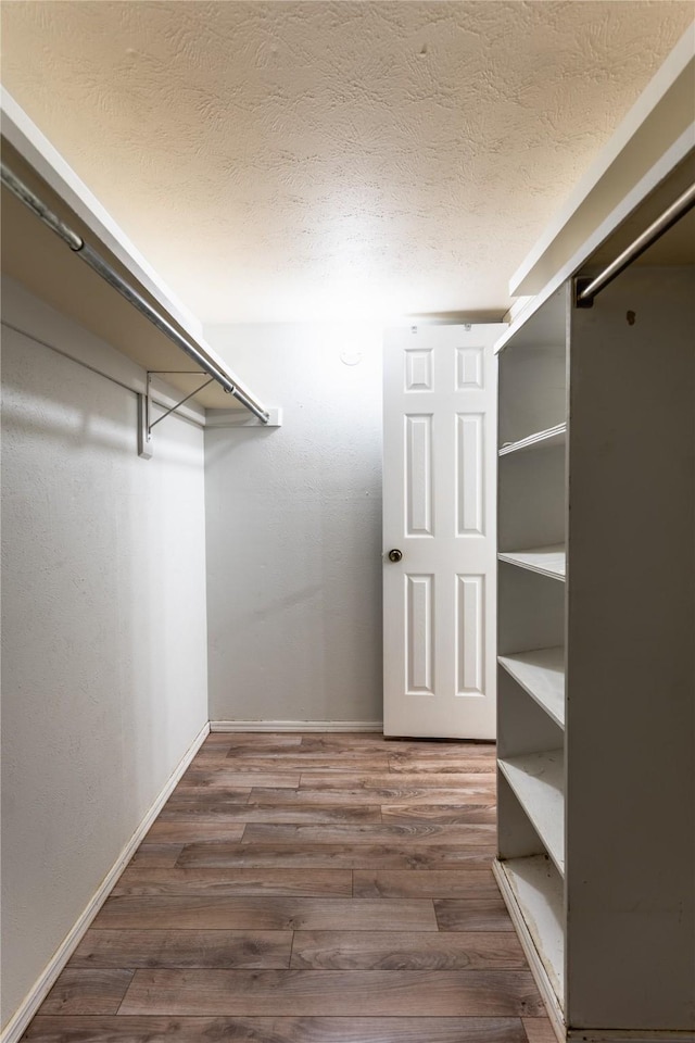 walk in closet with dark wood-style floors