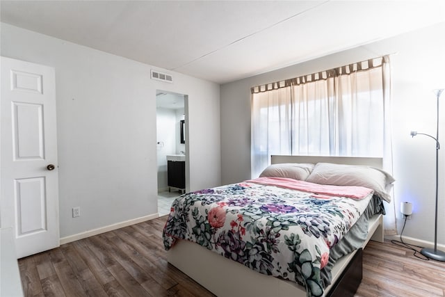 bedroom with visible vents, baseboards, ensuite bath, and wood finished floors