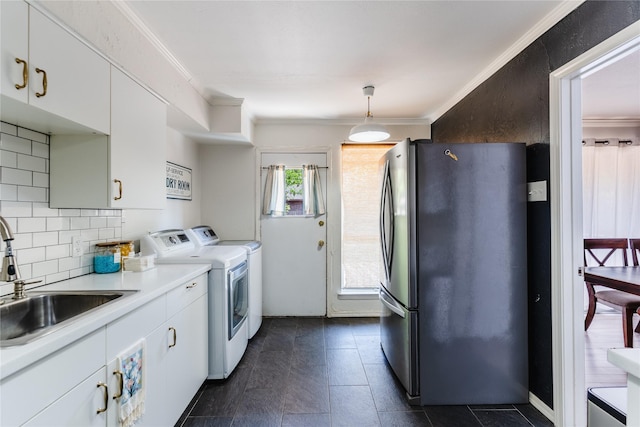 kitchen with freestanding refrigerator, ornamental molding, a sink, decorative backsplash, and washing machine and dryer