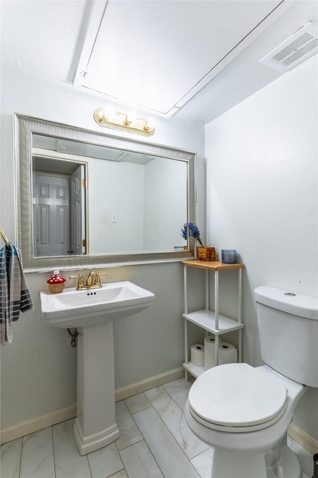 half bathroom featuring toilet, marble finish floor, baseboards, and visible vents