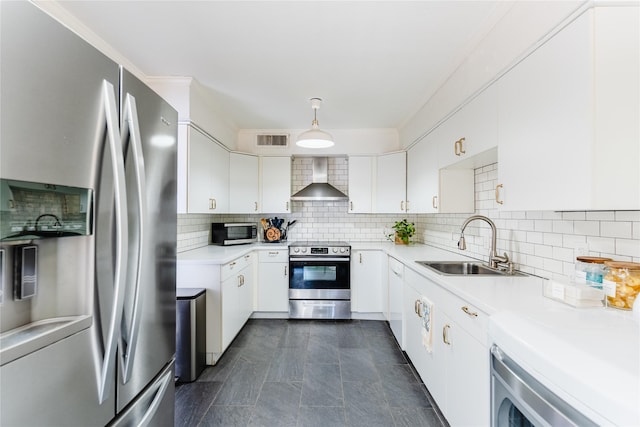 kitchen featuring wall chimney range hood, light countertops, visible vents, decorative backsplash, and appliances with stainless steel finishes