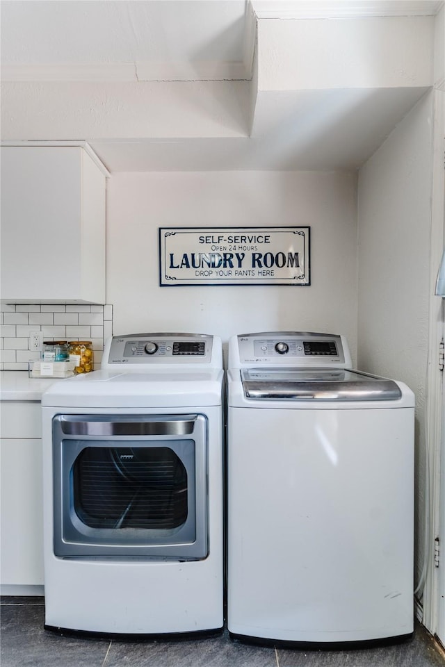 laundry room featuring washing machine and clothes dryer and cabinet space