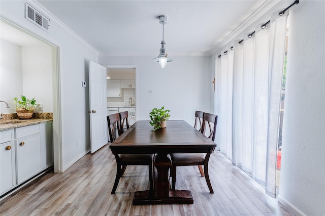 dining area featuring light wood-style flooring, baseboards, ornamental molding, and visible vents