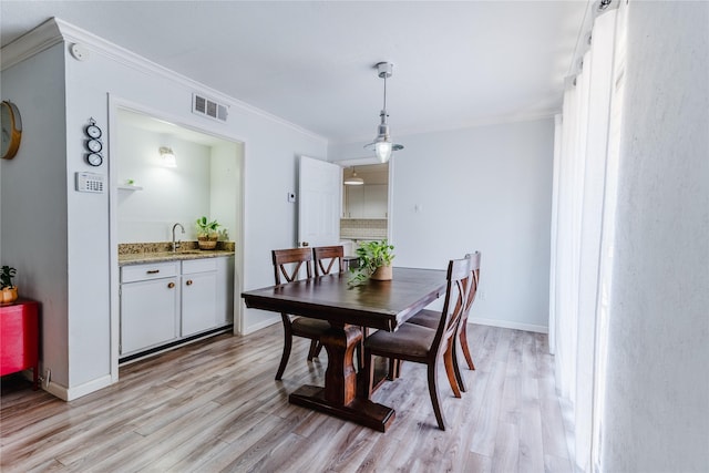dining area with ornamental molding, visible vents, baseboards, and light wood-style floors