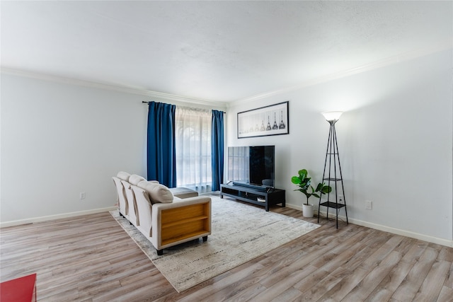living room featuring baseboards, crown molding, and wood finished floors