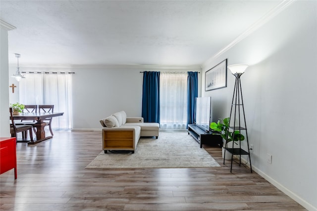living room with ornamental molding, baseboards, and wood finished floors