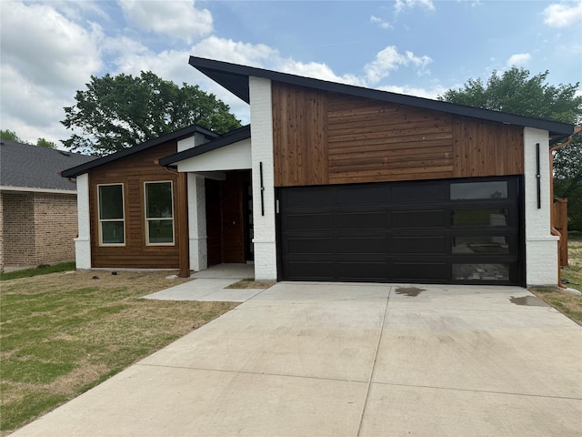 contemporary home with an attached garage, driveway, and a front lawn