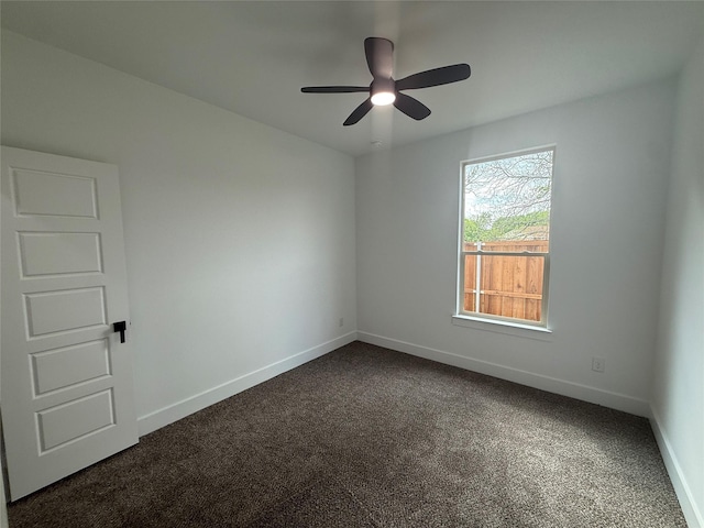 empty room featuring dark carpet, baseboards, and a ceiling fan