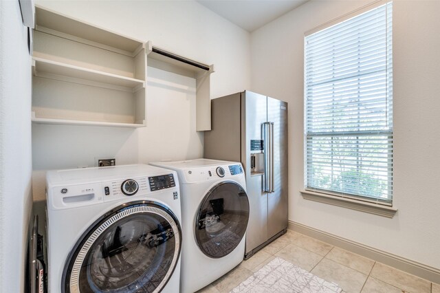 clothes washing area featuring laundry area, separate washer and dryer, light tile patterned floors, and baseboards