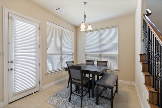 dining area with light tile patterned floors, baseboards, visible vents, and stairway